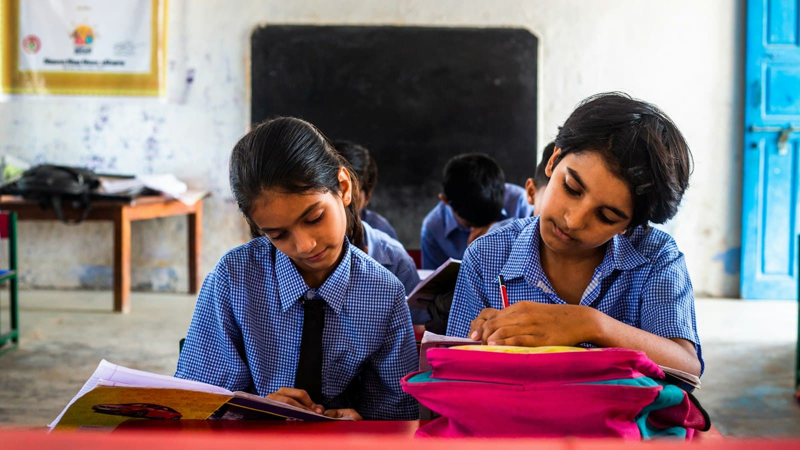 अपनी कॉपी में लिखती दो स्कूली छात्राएँ